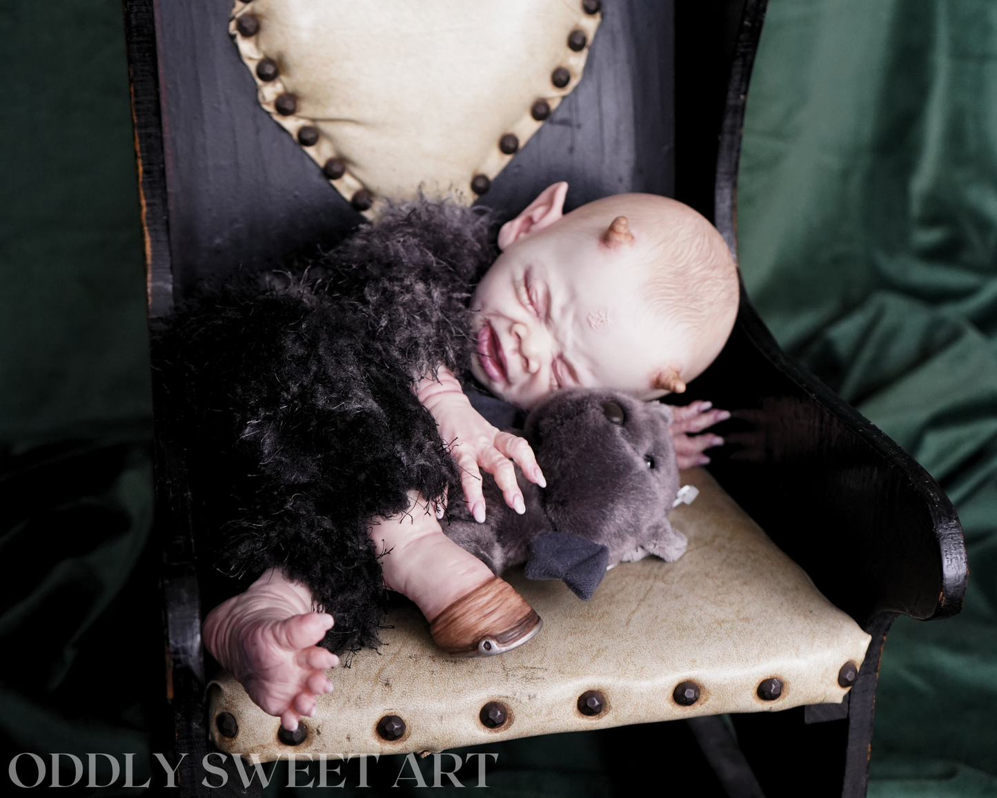 reborn baby doll fawn sitting on a black victorian rocking chair with bat