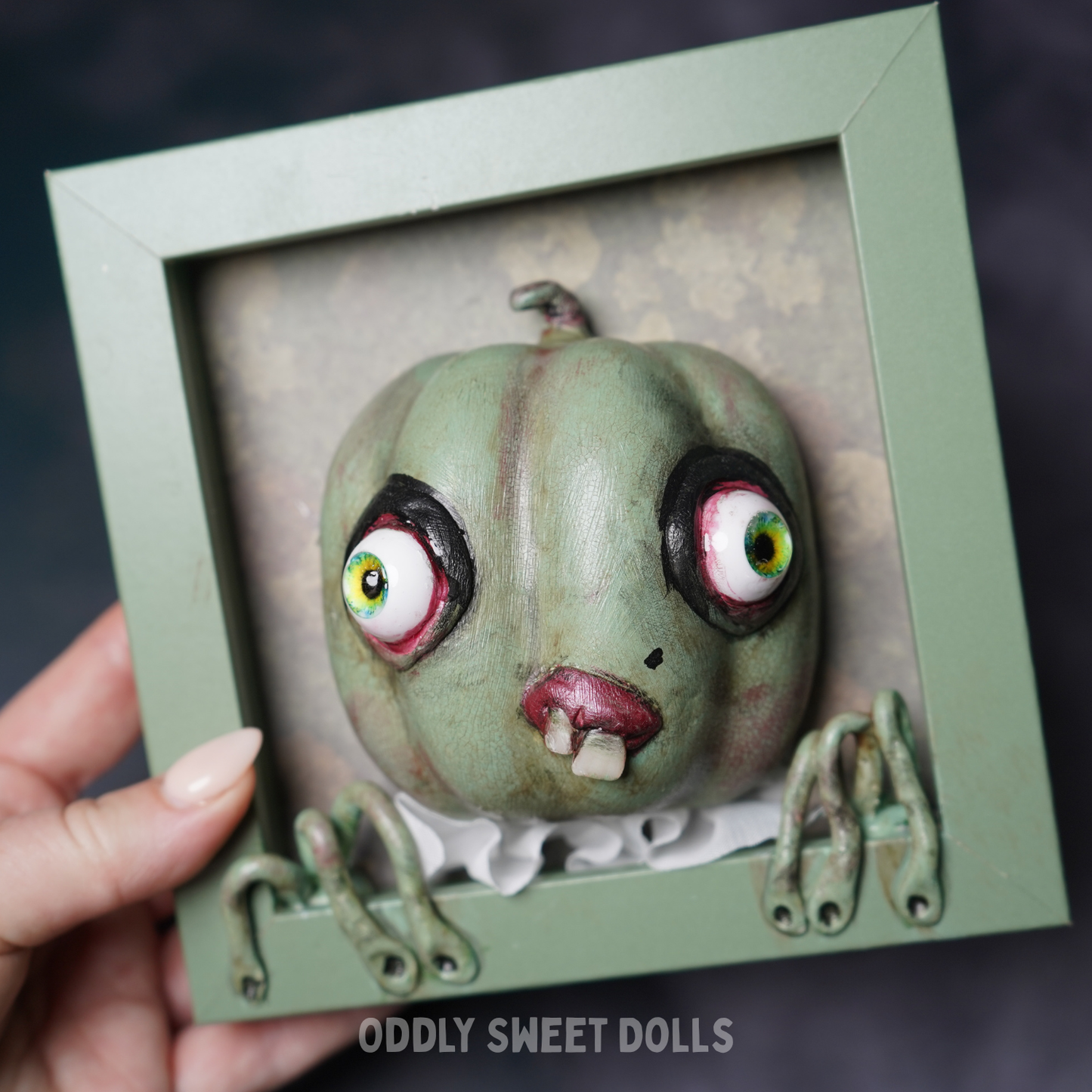 hand holding FRAMED PUMPKIN with big eyes and teeth