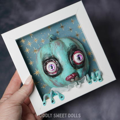 hand holding white frame pumpkin with big eyes and teeth