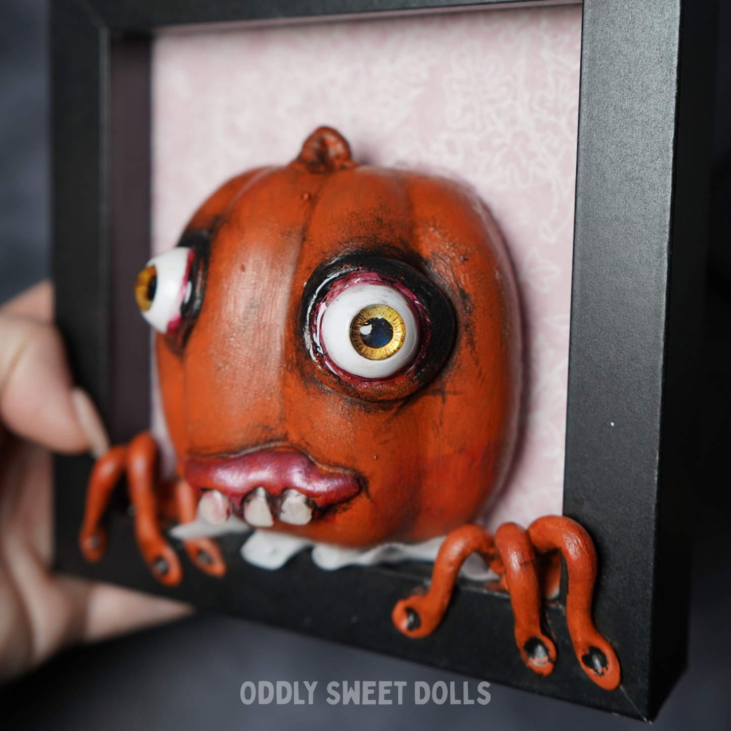 pumpkin in black frame with big eyes and teeth