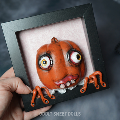 pumpkin in black frame with big eyes and teeth