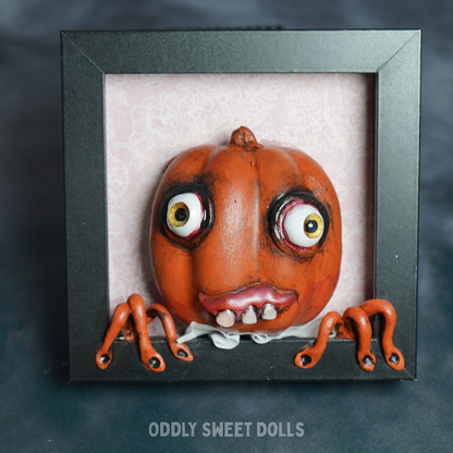 pumpkin in black frame with big eyes and teeth