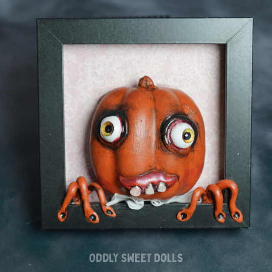 pumpkin in black frame with big eyes and teeth