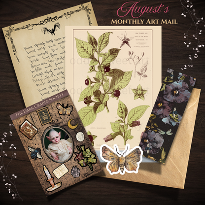 A styled flat lay of a monthly art mail card set from August, featuring vintage botanical illustrations, a handwritten letter, a floral envelope, and a decorative card from The Dark Cackle Society on a dark wood background.