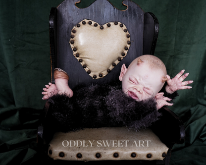reborn baby doll fawn sitting on a black vitorican rocking chair
