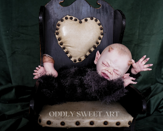 reborn baby doll fawn sitting on a black vitorican rocking chair