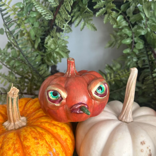 Decorative pumpkins with painted faces on a green leafy background