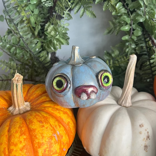 Decorative pumpkins with a painted face on a green leafy background