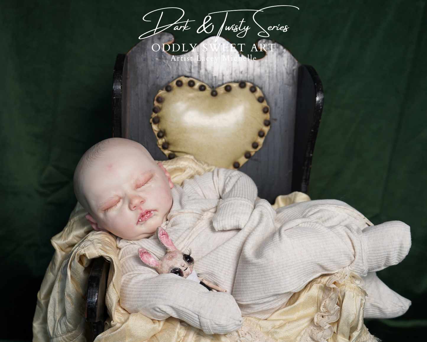 A realistic sleeping doll or baby figure dressed in cream ribbed clothing, posed on a vintage dark wooden chair with a heart-shaped cushion against a dark green backdrop. A small stuffed bunny rests near the figure.