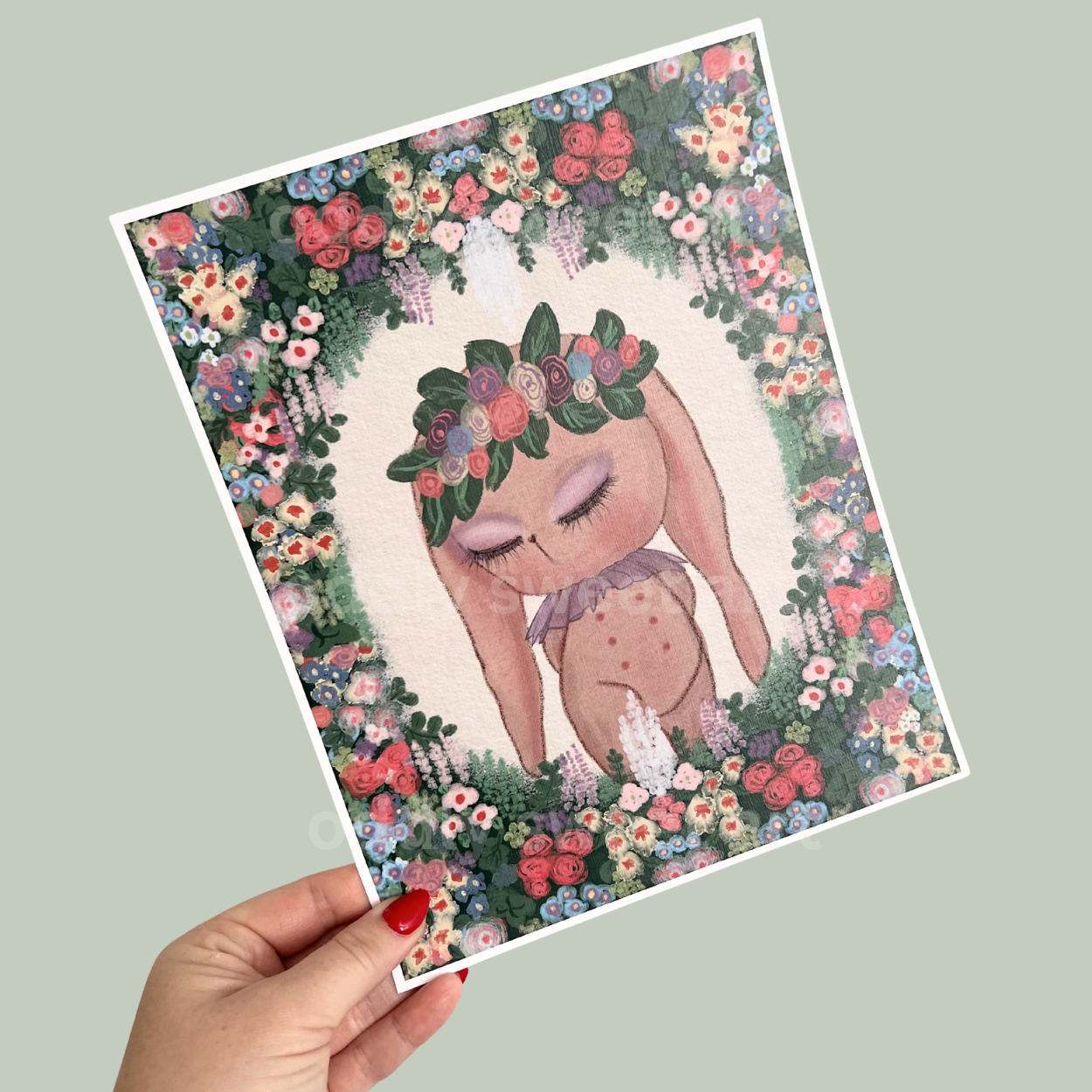 Illustration of a bunny with a floral crown held by a hand on a light gray background