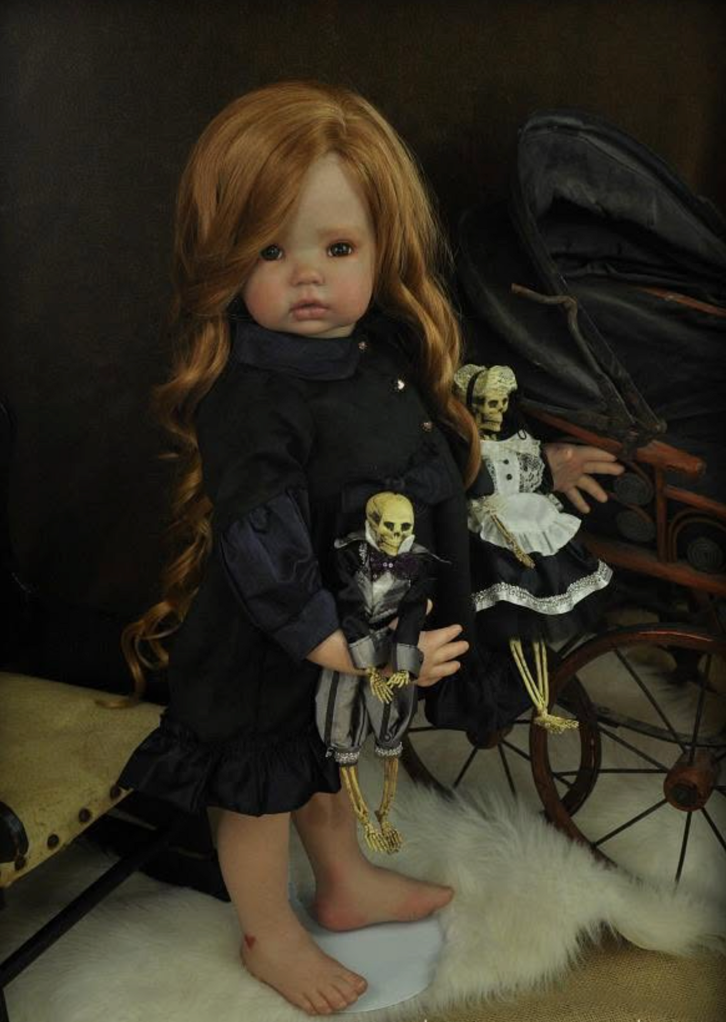 A gothic-style porcelain doll with long red hair, wearing a black dress, standing barefoot on a white faux-fur rug next to a black stroller with skeleton dolls inside.